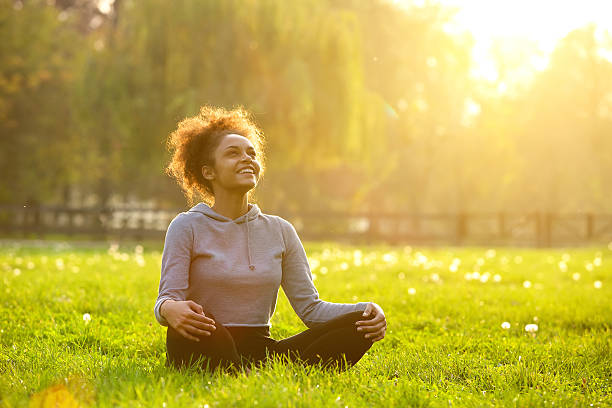 Happy young woman sitting in yoga position Happy young woman sitting outdoors in yoga position fitness body stock pictures, royalty-free photos & images