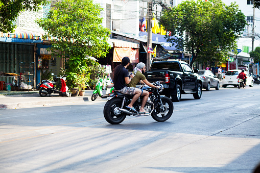Bangkok, Thailand - January 18, 2015: Two thai guys are driving on a motorbike in Bangkok. None of them is wearing a helmet. Scene is in street Chokchai 4. Ladprao.