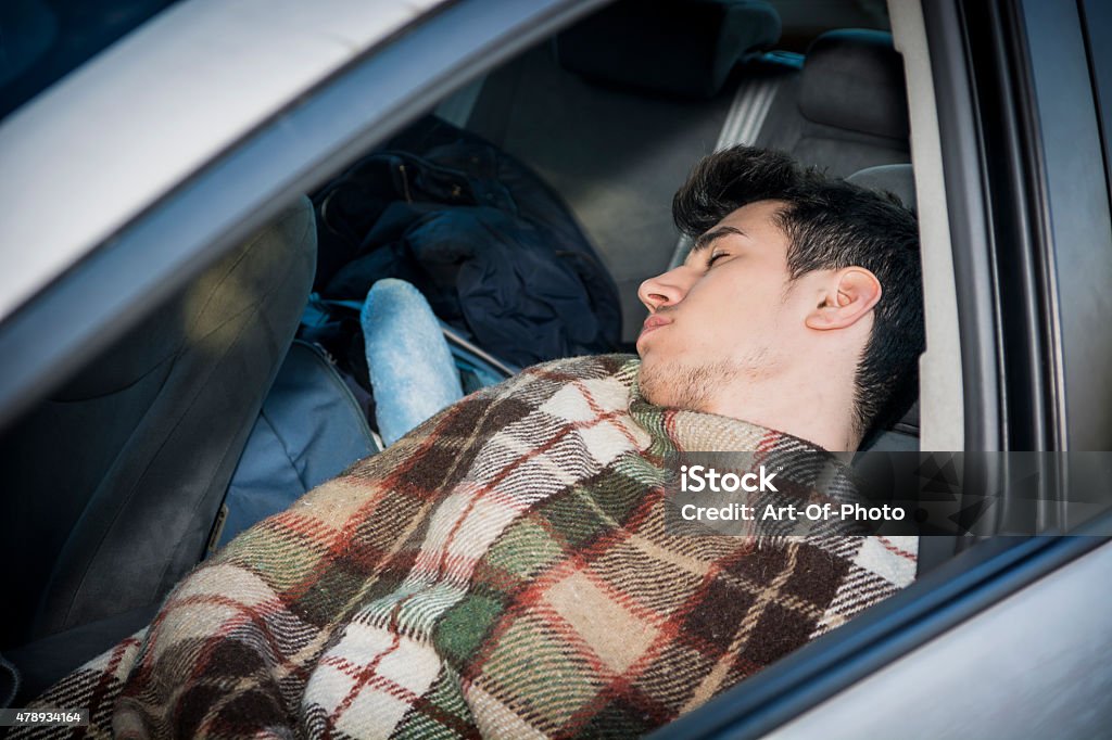 Joven handosme hombre durmiendo en su coche - Foto de stock de Coche libre de derechos