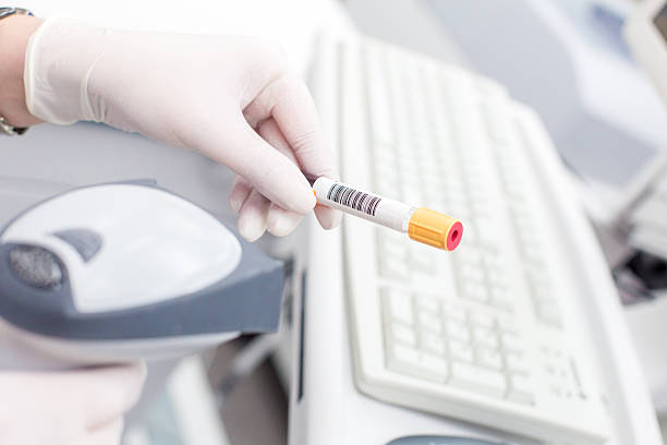 Scanning barcode on tube in white medical lab by nurse Scanning the bar code on the tube in white medical lab by nurse in white rubber gloves. In the background is a computer keyboard with the mouse. In the foreground a laser barcode scanner. traceability stock pictures, royalty-free photos & images