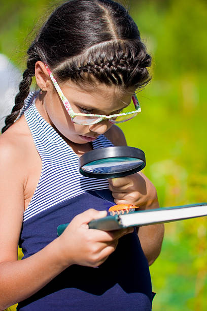 istock girl looking through magnifying glass on beetle 478940893