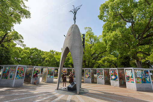 Hiroshima, Japan - May 22, 2015: Japanese school girls visiting the Children's Peace Monument in Hiroshima. Dedicated to Sadako Sasaki, a girl who was only 2 at the time of the bombing. She survived but contracted leukemia and died at age 12. Her classmates were motivated to have this monument built as a memorial to all children killed by the atomic bomb.