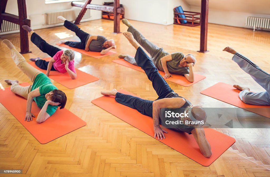 Above view of large group of seniors exercising at class. High angle view of group of old people doing relaxation exercises in a health club. Health Club Stock Photo