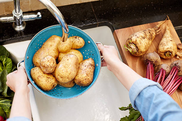istock Woman washing potatoes in colander at kitchen 478955080