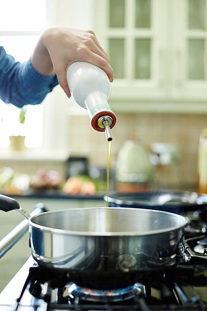 istock Woman's hand adding oil in frying pan 478955360