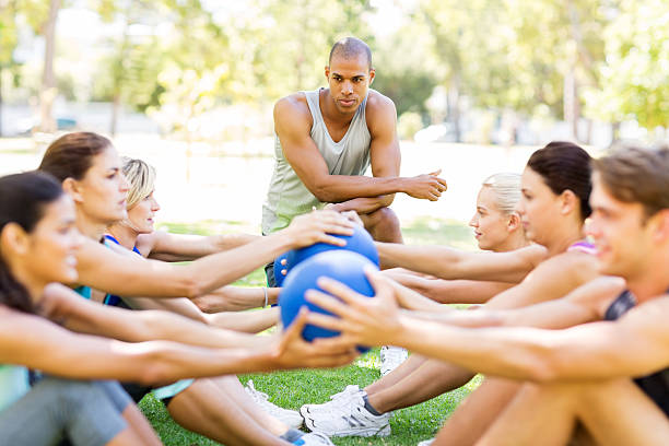 istock Instructor Motivating People Exercising With Medicine Balls In P 478956354