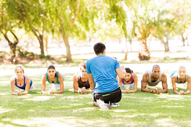 istock Personal Trainer Motivating People In Doing Exercise At Park 478961168