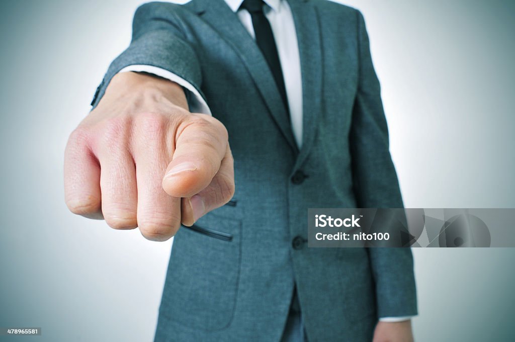 man in suit pointing the finger man wearing a suit sitting in a table pointing the finger to the observer Adult Stock Photo