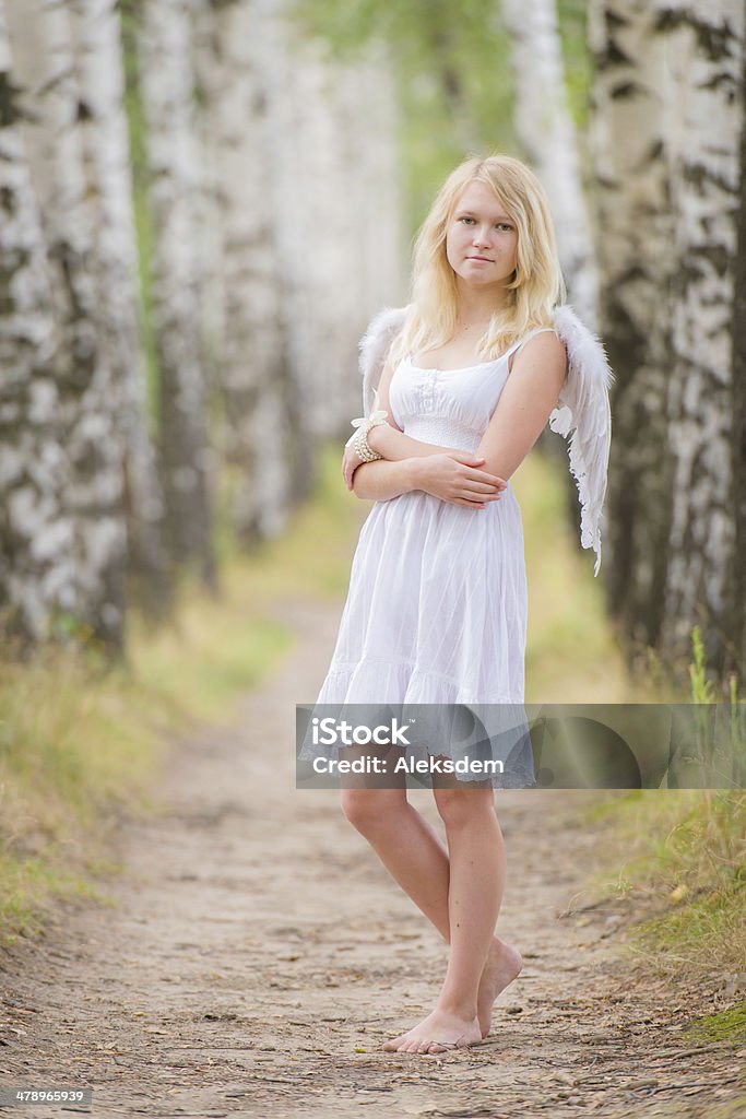 Young woman with angel wings on back Barefoot young woman in a white dress with angel wings on the back. Photographing in a birch grove. Angel Stock Photo