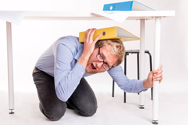 Man in under a desk during the earthquake stock photo