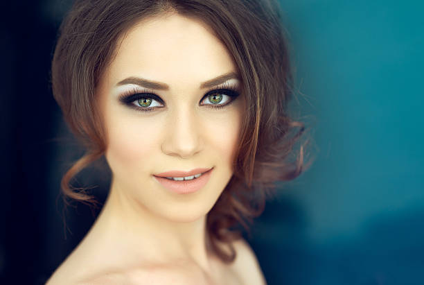 attractive woman with green eyes smiling, professional makeup and hairstyle, looking at camera.