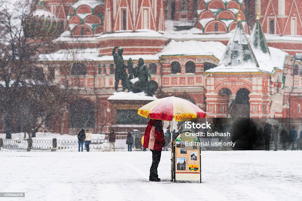 Professional photographer by his open air stand on Red Square Moscow, Russia - February 4, 2013: Moscow, Russia, February 4, 2013. Heavy snowstorm. Professional photographer gets out of the snow under his umbrella. St. Basil's cathedral in the background 2015 Stock Photo