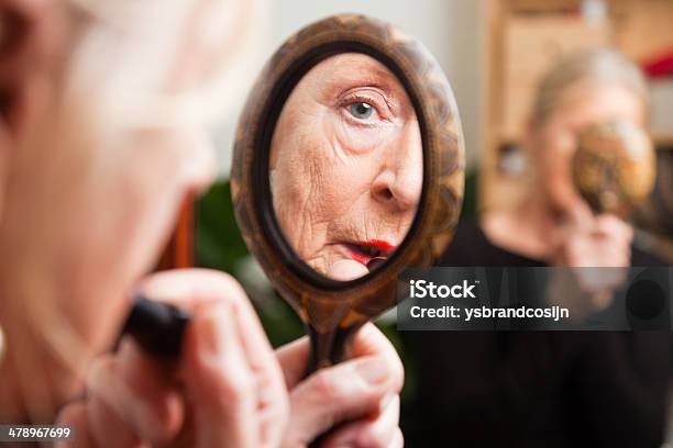Good Looking Senior Woman Doing Lipstick In Front Of Mirror Stock Photo - Download Image Now