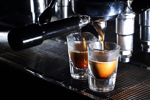 Professional espresso machine brewing a coffee. Coffee pouring into shot glasses