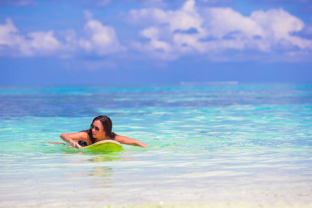 istock Young slender surf girl at white beach with yellow surfboard 478971156