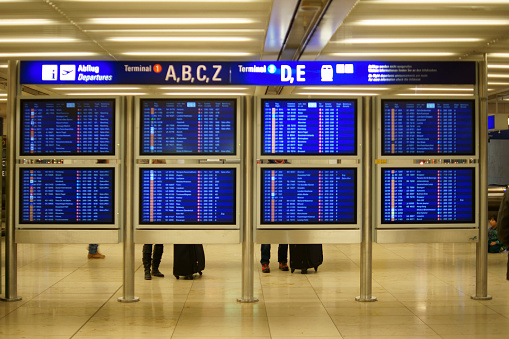 Frankfurt, Germany - November 27, 2014: Travelers standing and waiting at the digital display and information board for departures in the Frankfurt airport on November 27, 2014 in Frankfurt.
