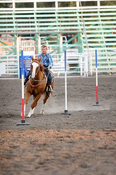 Cowboy running poles on his horse in an arena during fair