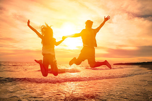 istock young happy couple jumping on beach 478978154