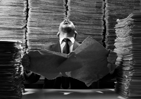 Office worker tearing up papers and screaming out due to red tape