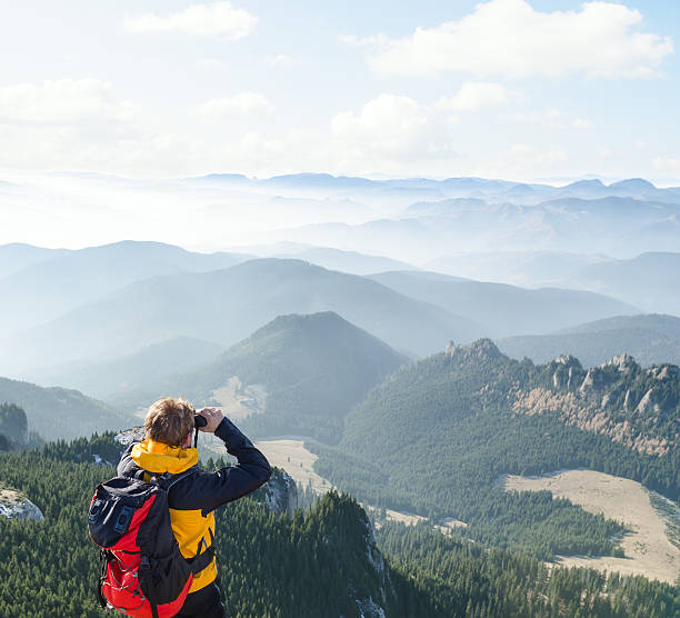 Mountaineer looking over the hills through  binoculars