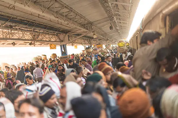 Main train station in Calcutta is crowded all day and night. India. Large group of people walking at the railway station and traing to get on already crowded train.