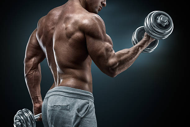 istock Power athletic man in training pumping up muscles with dumbbells 478984970