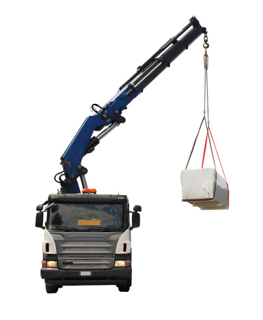 A truck with a telescopic crane delivers packages containing a wood (fir) block house, a pre-cut wooden house which is assembled on-site