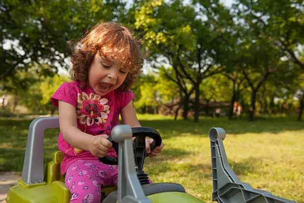 Cute little girl driving toy excavator at children park