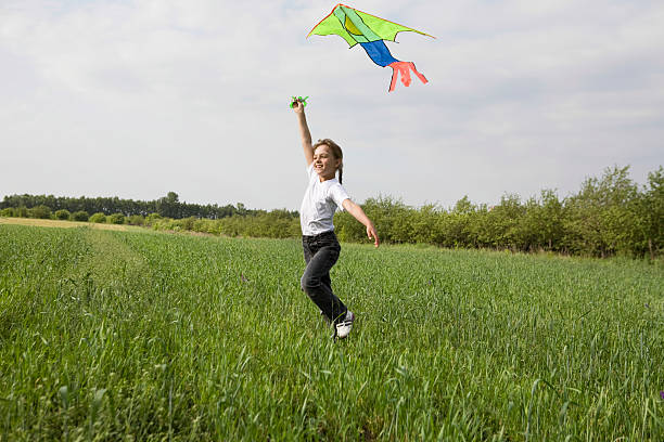 istock Young Girl Flying Kite In Field 478987753