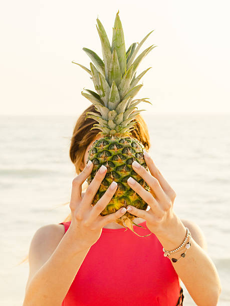 istock Young Woman Holding Pineapple On The Beach 478988462