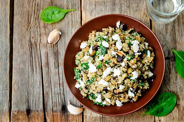 quinoa spinach eggplant feta salad on a dark wood background. the toning. selective focus