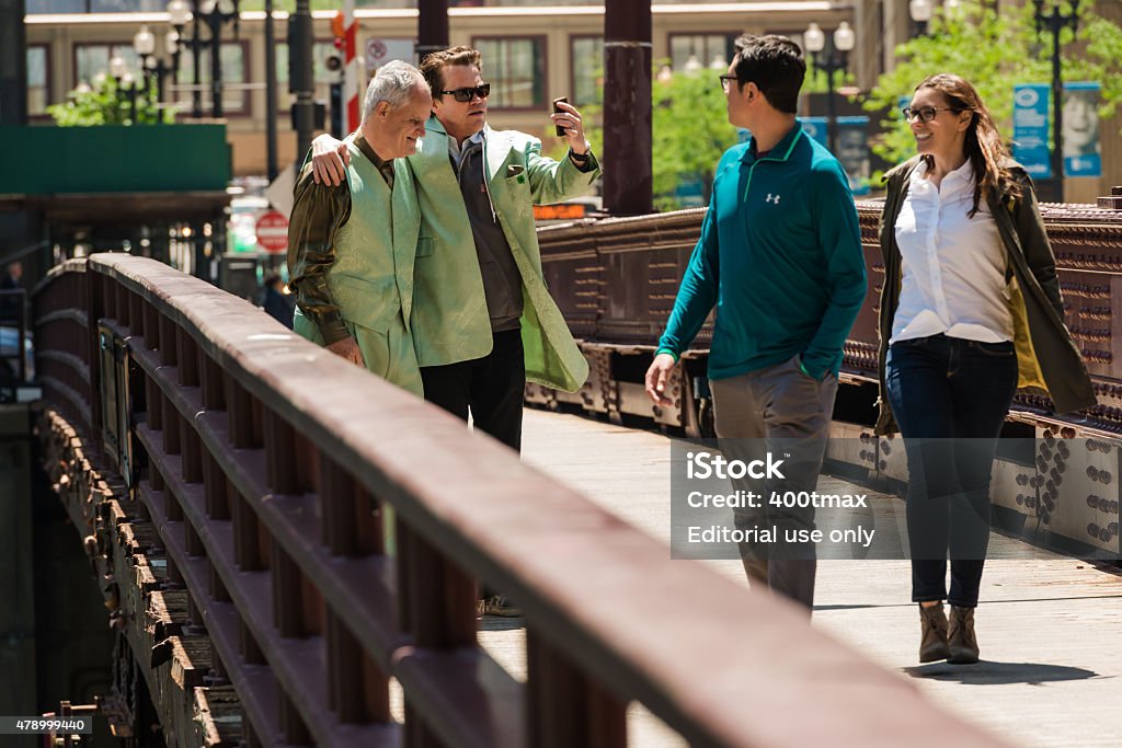 Chicago Chicago, USA - June 2, 2015: A man wearing a bright green suit posing with a passerby on the Dearborn street bridge over the Chicago river mid day.  2015 Stock Photo