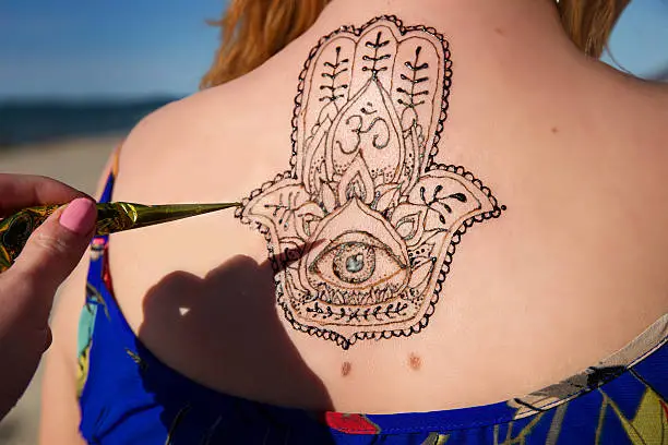 Photo of henna tattoo mehendy painted on back hamsa