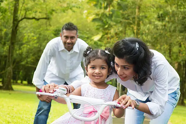 Photo of Indian  parent teaching child to ride a bike