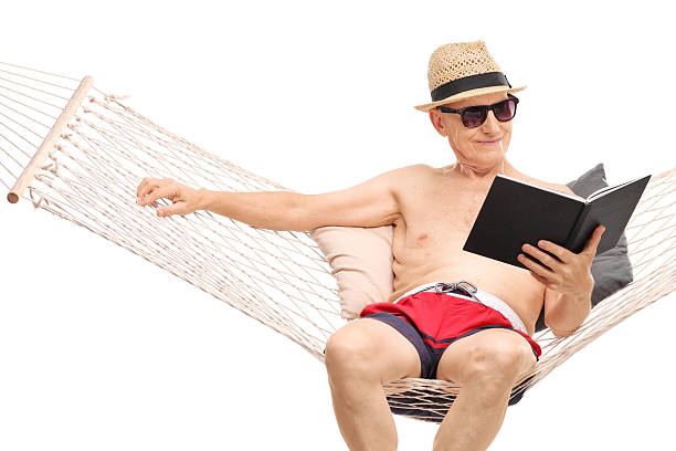 istock Relaxed senior sitting in a hammock and reading a book 479016074