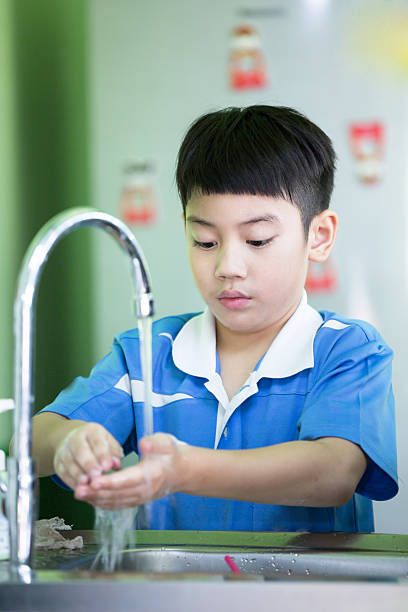 Little asian boy washing his hands in the kitchen room stock photo