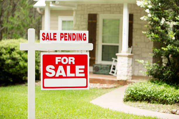 House for sale, pending sign in front yard. No people. Red and white "Sale Pending, Home for Sale" sign in front of a stone, wood house that is for sale and has recently been sold. Green grass and bushes indicate the spring or summer season. Front porch and windows in background. Real estate signs in residential neighborhood. Moving house, relocation concepts. house for sale sign stock pictures, royalty-free photos & images