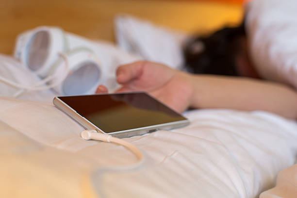 istock hand holding smartphone and headset when sleeping on bed 479030042