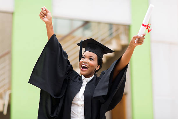 afro american female graduate standing in front of university building stock photo