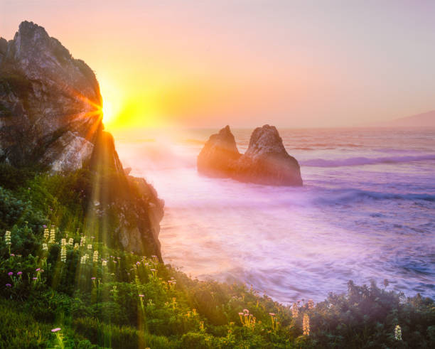 Rocky shoreline of Big Sur area of California with sunburst rays