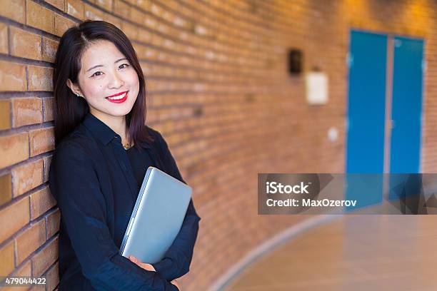 Asian College Student Standing At The Brick Wall With Laptop Stock Photo - Download Image Now