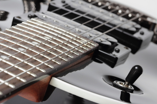 Part of an elegant black electric guitar - fretboard and humbuckers close-up.