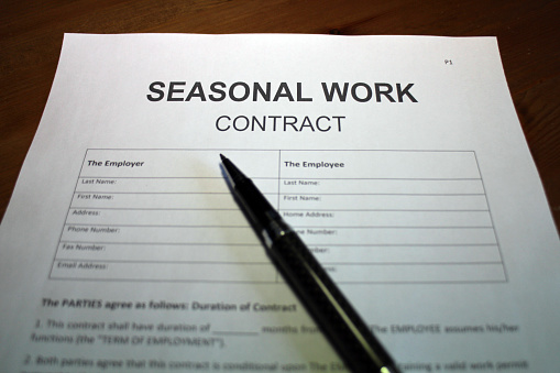 Someone filling out seasonal work contract agreement.