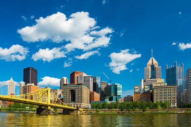 Photo of Pittsburgh downtown skyline, bridge, river, and puffy cumulus clouds