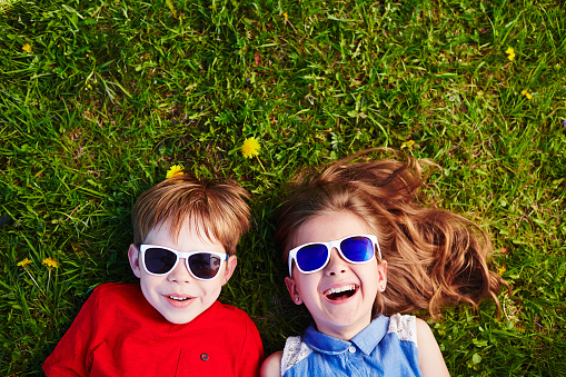 Carefree friends in sunglasses lying on green grass