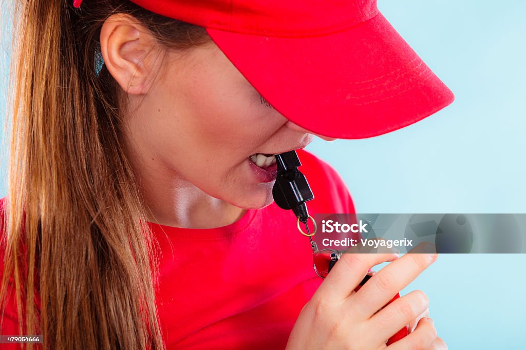 lifeguard on duty blowing a whistle Accident prevention and water rescue. Closeup girl in red lifeguard outfit on duty blowing a whistle on blue Whistle Stock Photo