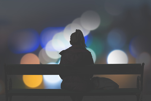 Silhouette of a girl watching defocused city lights.