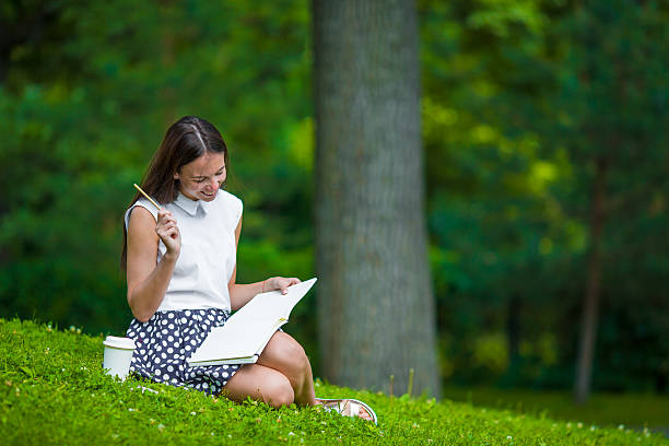 istock Young girl writing in her notebook outside at park 479061810