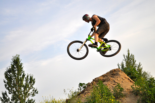 Warsaw, Poland - June 24, 2012: BMX acrobatic rider flies through the air on a bike, during local Dirt jumping game, without an audience, on the outskirts of Kazura housing estate.
