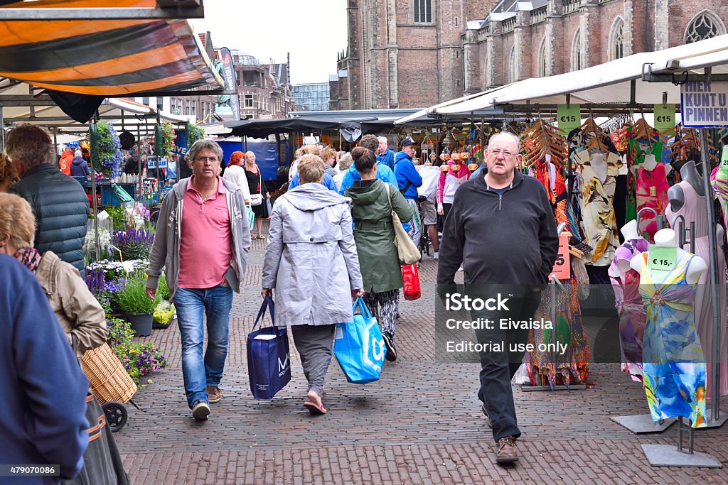 Market place with various products. Haarlem, Netherlands - June 13, 2015: Outdoor market on the town square of Haarlem. Weekly market with various products. Market stall showing clothes and flowers. People walking over the market place. Haarlem Stock Photo